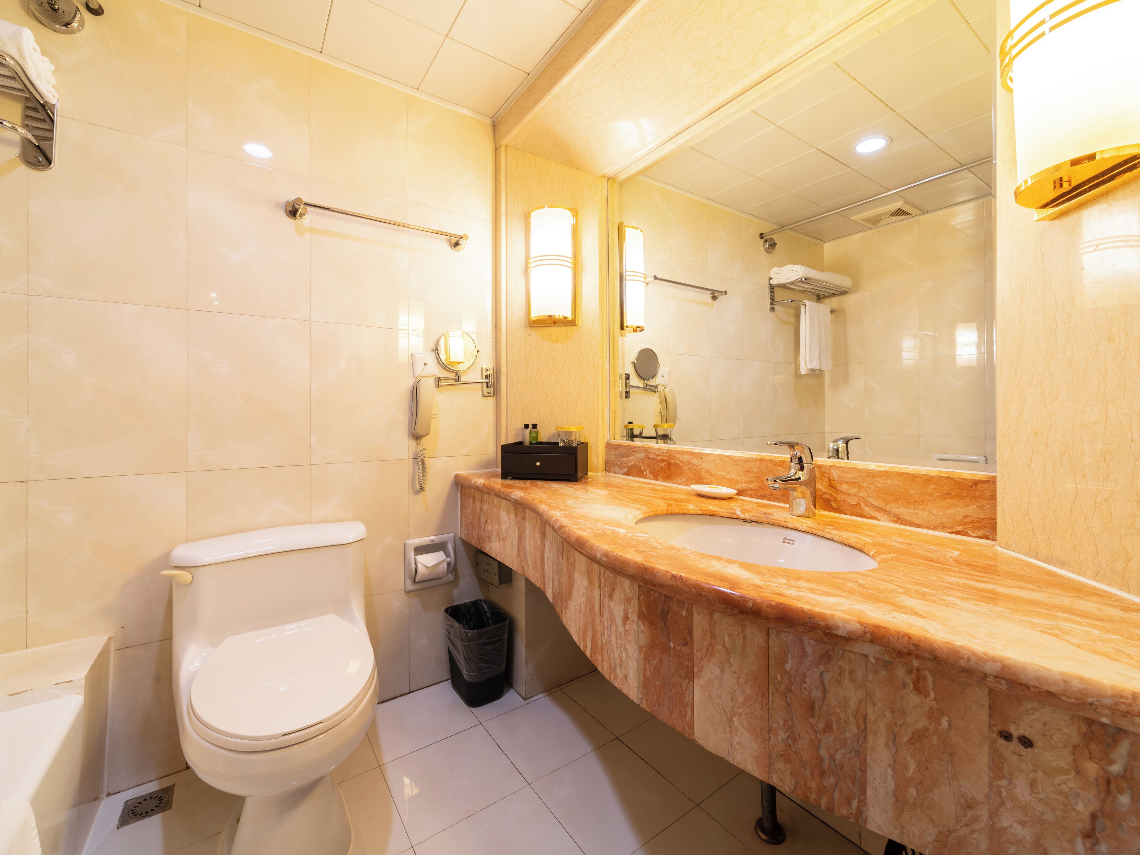 A modern bathroom with a white toilet, a sink with a marble countertop, and a large mirror.