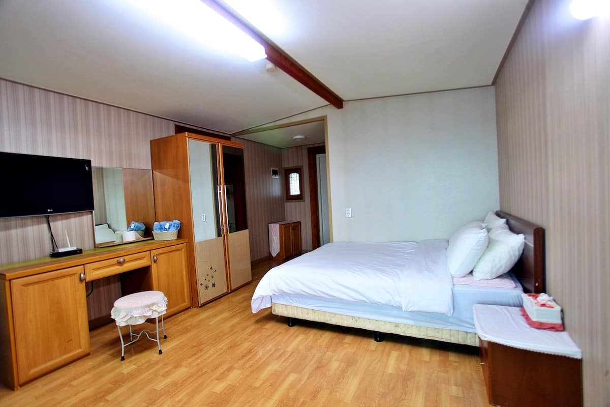 Une chambre à coucher comprenant un lit, un bureau, une télévision et une armoire.