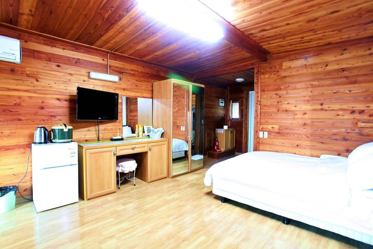 Une chambre dans un chalet en bois, comprenant un lit, un bureau, une télévision et une petite kitchenette.