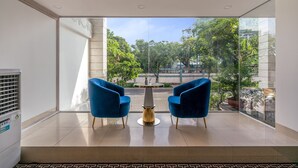 A modern room with a large window, two blue chairs, a small table, and a radiator.