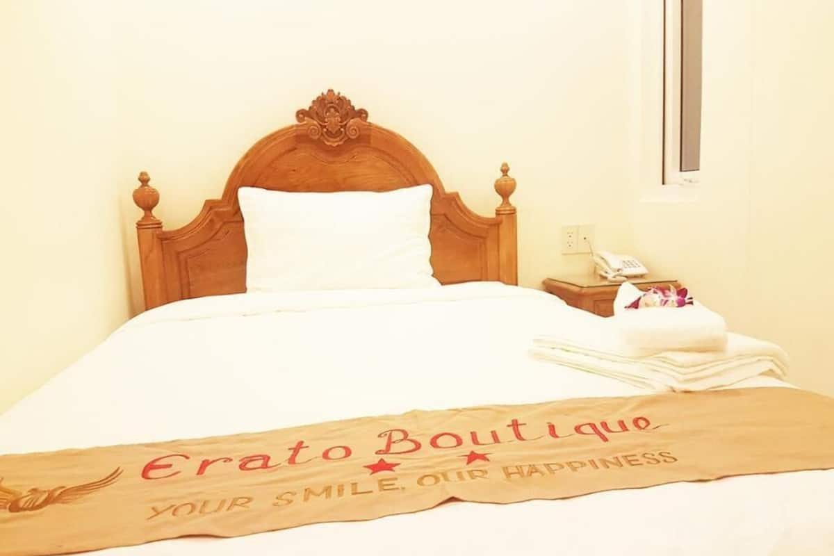 A neatly made bed with a wooden headboard, a white pillow, and a blanket with a message.