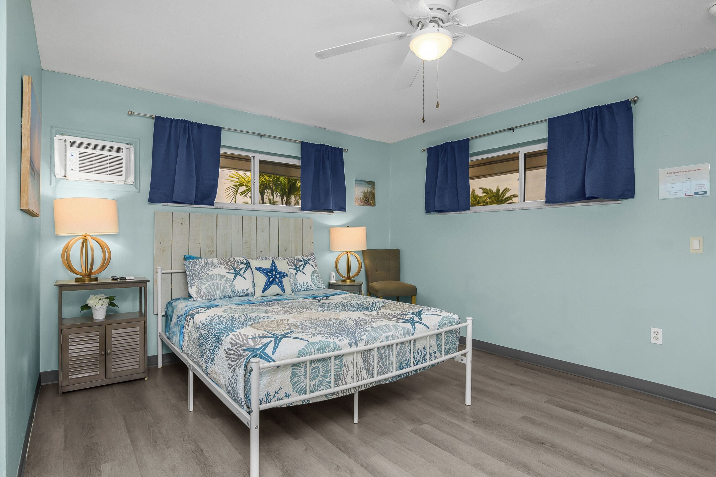 A bedroom with a bed, two bedside tables, a ceiling fan, and a window with curtains.