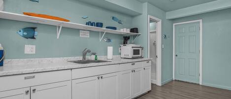 A kitchen with white cabinets, a marble countertop, and a microwave.