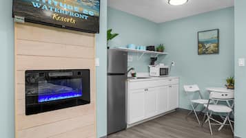 Een moderne keuken met een ingebouwd aquarium, witte kasten en een klein eethoekje met stoelen.