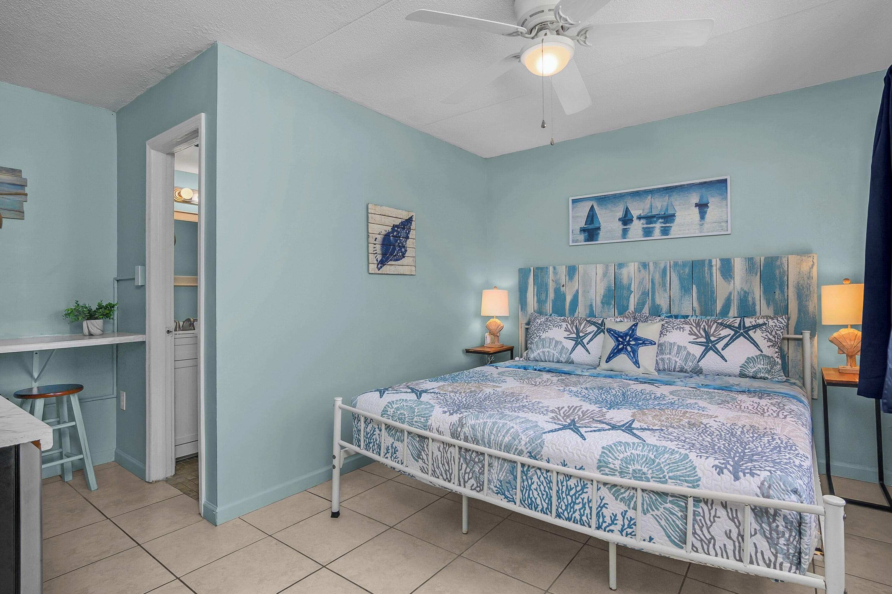 A bedroom with a bed, a desk, and a chair.