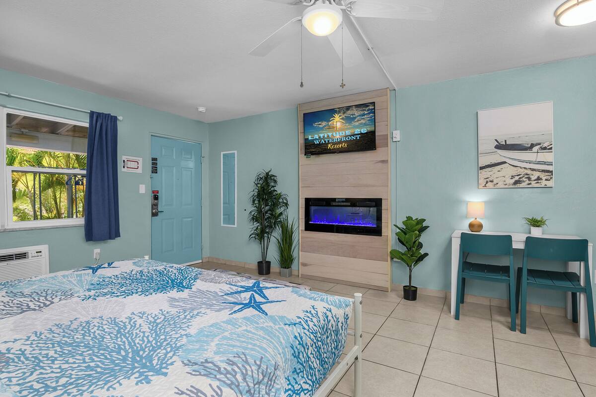 A room with a bed, a desk, a TV, and a ceiling fan.