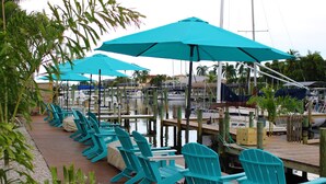 A marina with rows of blue Adirondack chairs under turquoise umbrellas, wooden docks, and boats. - Latitude 26 Waterfront Boutique Resort - Fort Myers Beach (Fort Myers Beach)