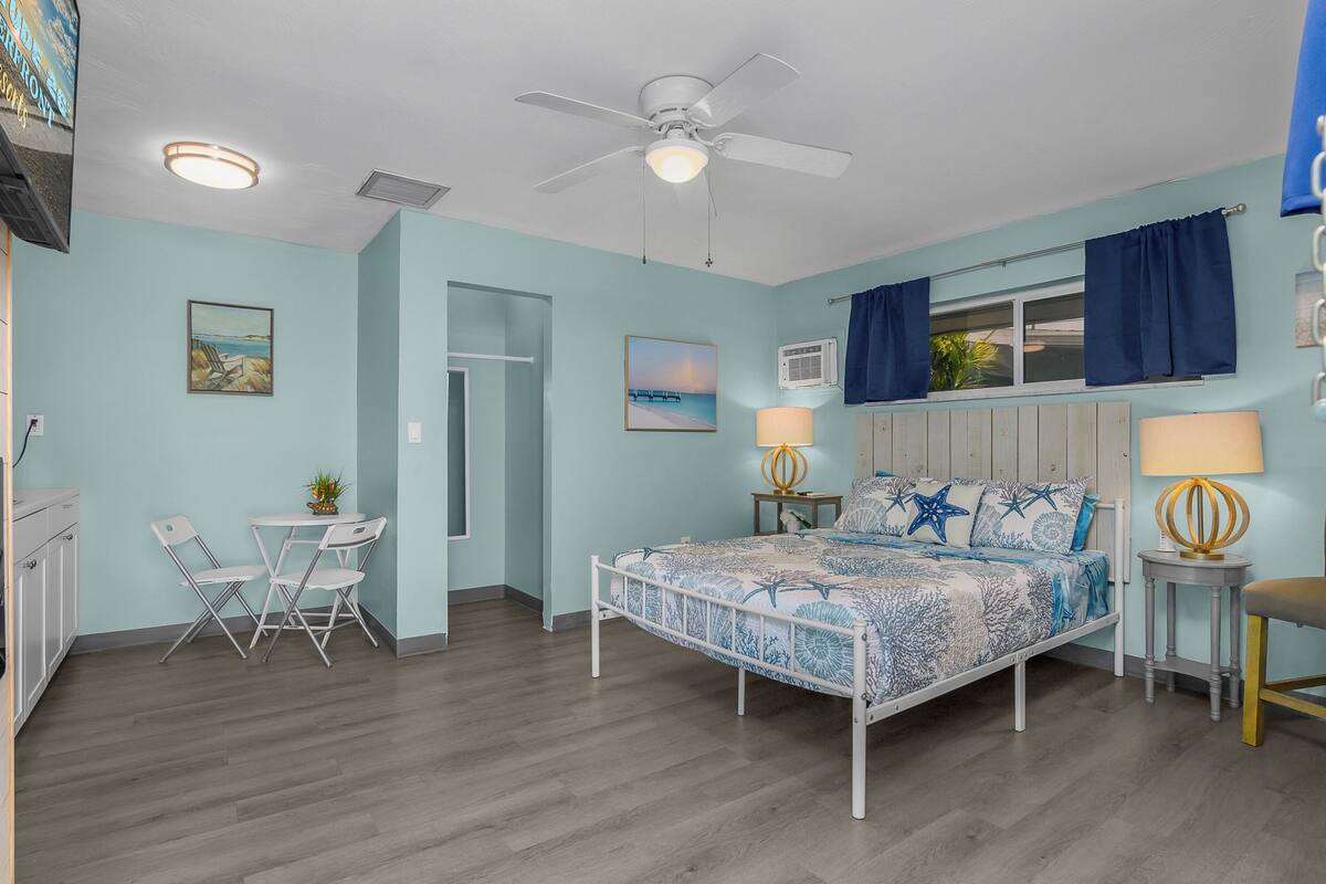 A bedroom with a bed, two bedside tables, a ceiling fan, and a window with curtains.