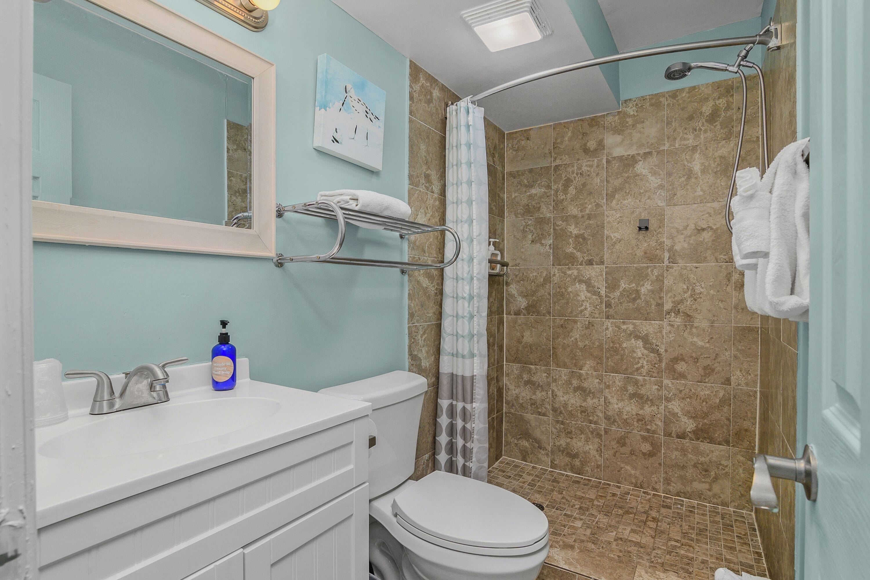 A bathroom with a white sink, a toilet, a shower with a glass door, and a towel rack.