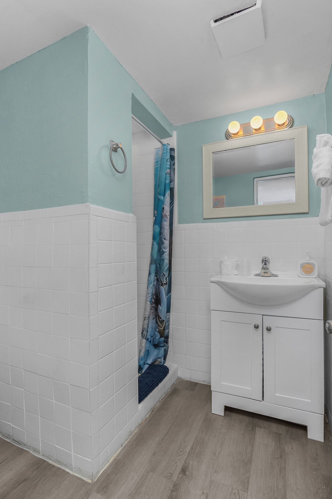 A bathroom with a shower, a sink, and a mirror with lights.