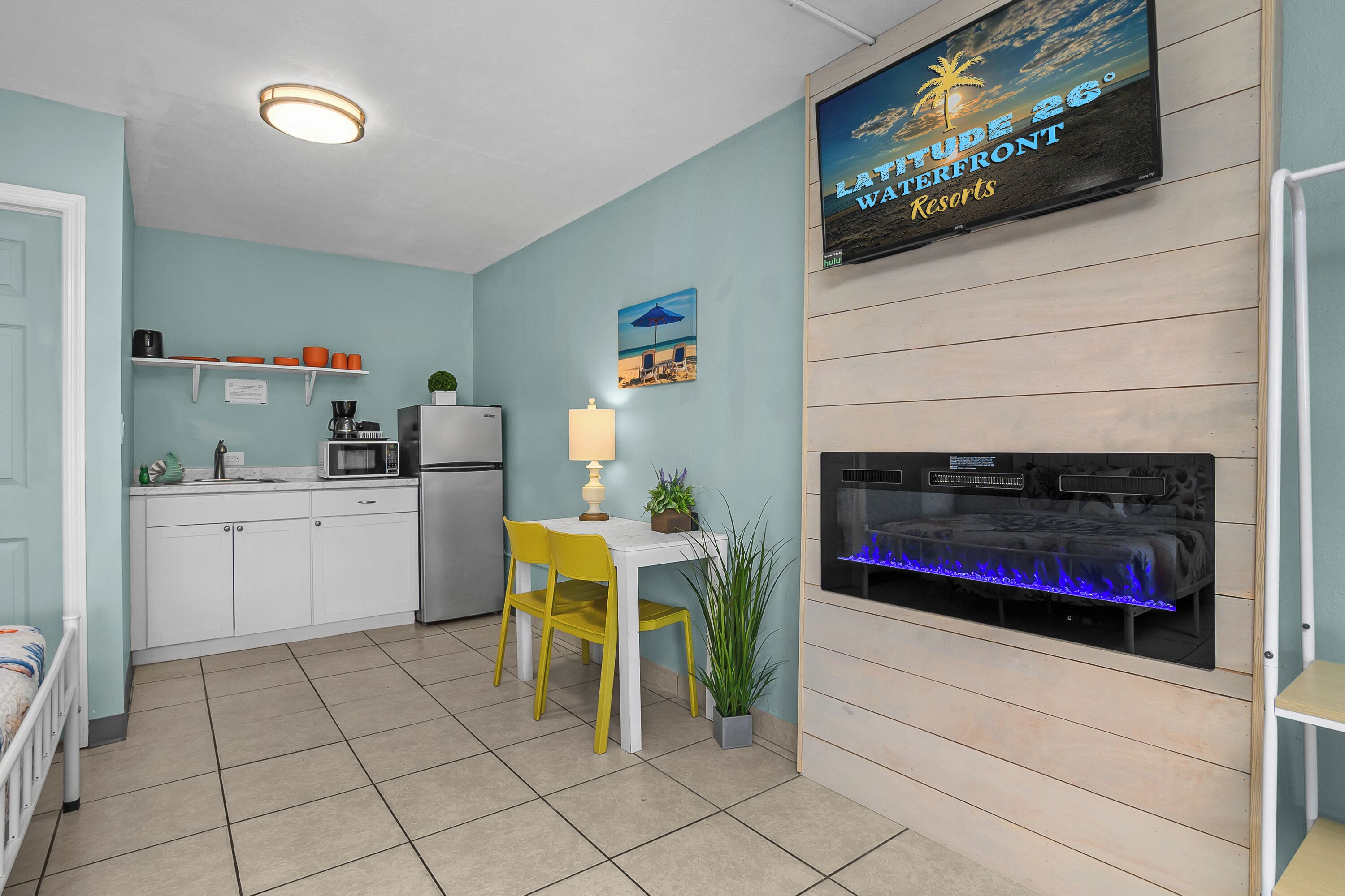 Une cuisine compacte avec des meubles blancs, un four à micro-ondes et un petit coin repas agrémenté de chaises jaunes.