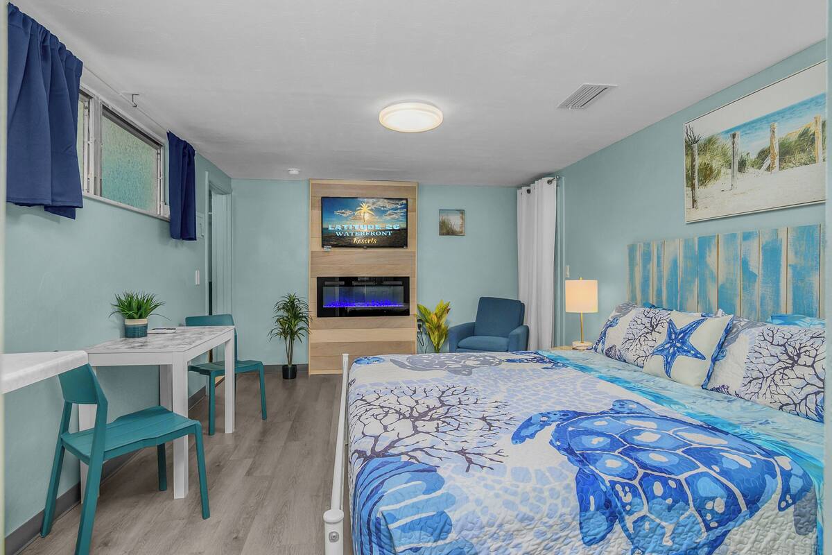 A bedroom with a bed, a TV, a desk, and chairs.