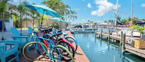 A dock with bicycles, a boat, and a building with a balcony.