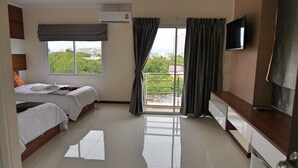 Una camera d'albergo con due letti, televisione, un balcone con tende e vista sulla città.
