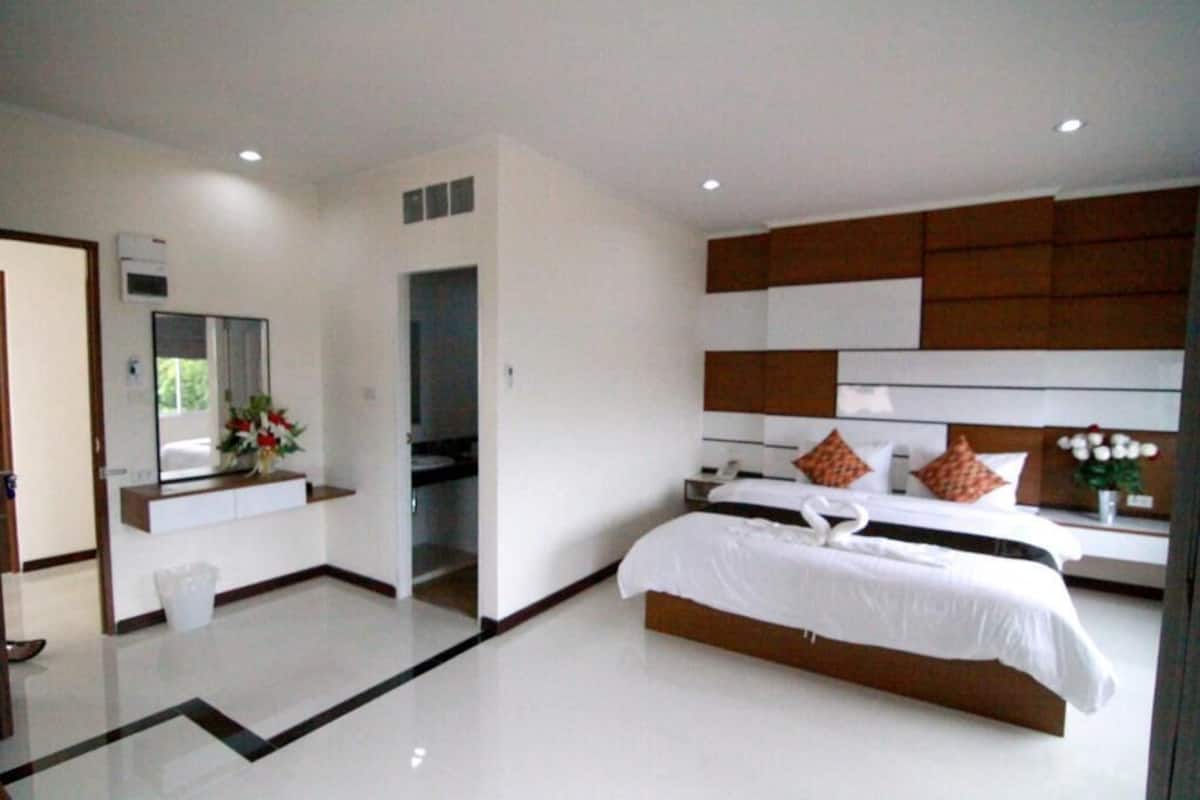 A modern hotel room with a large bed, a vanity with a mirror, and a small bathroom.