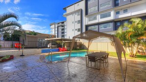 A modern apartment building with a swimming pool, outdoor seating, and a covered patio area. - Bay Air Motel (Cleveland)