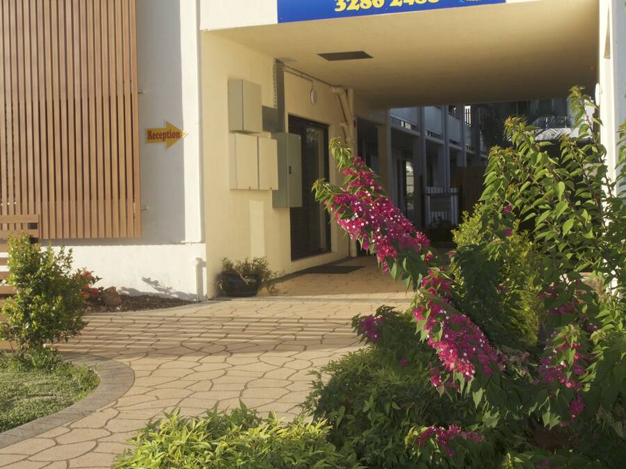 The exterior of Bay Air Motel with a reception sign, a paved walkway, and surrounding greenery.