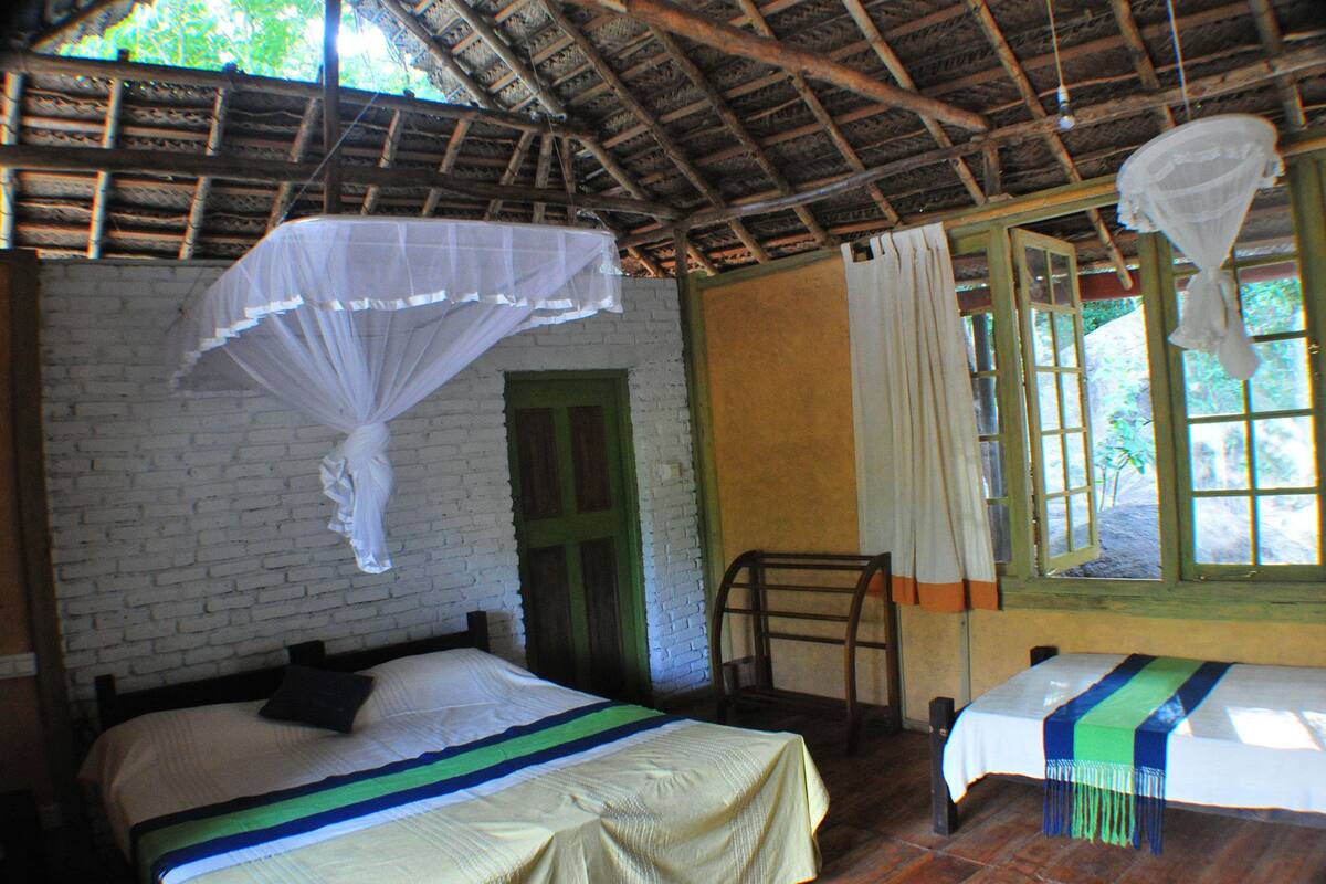 A room with a bed, a chair, a window, and a mosquito net.