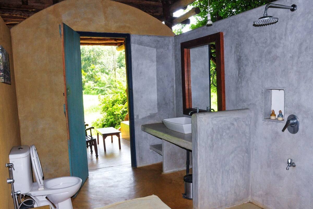 A bathroom with a toilet, sink, shower, and a view of the outdoors.