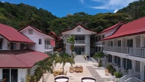 Et hotel med en central gårdsplads, flere balkoner og et bjerglandskab i baggrunden.