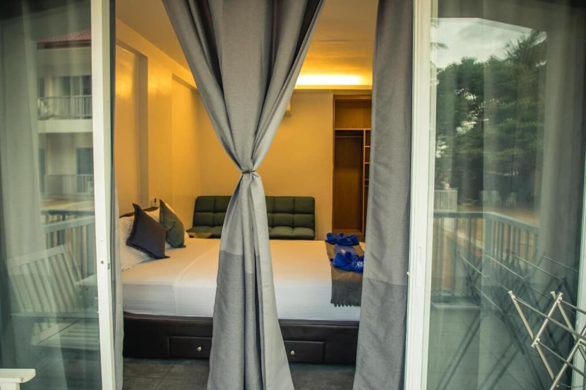 A bedroom with a bed, pillows, a bedside table, and a window with curtains.
