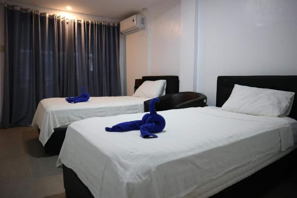 Two single beds with white linens, a black headboard, and a blue towel sculpture on each bed.