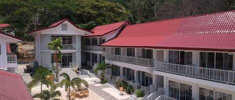A hotel with multiple floors, red-tiled roofs, and outdoor seating areas with cushions.