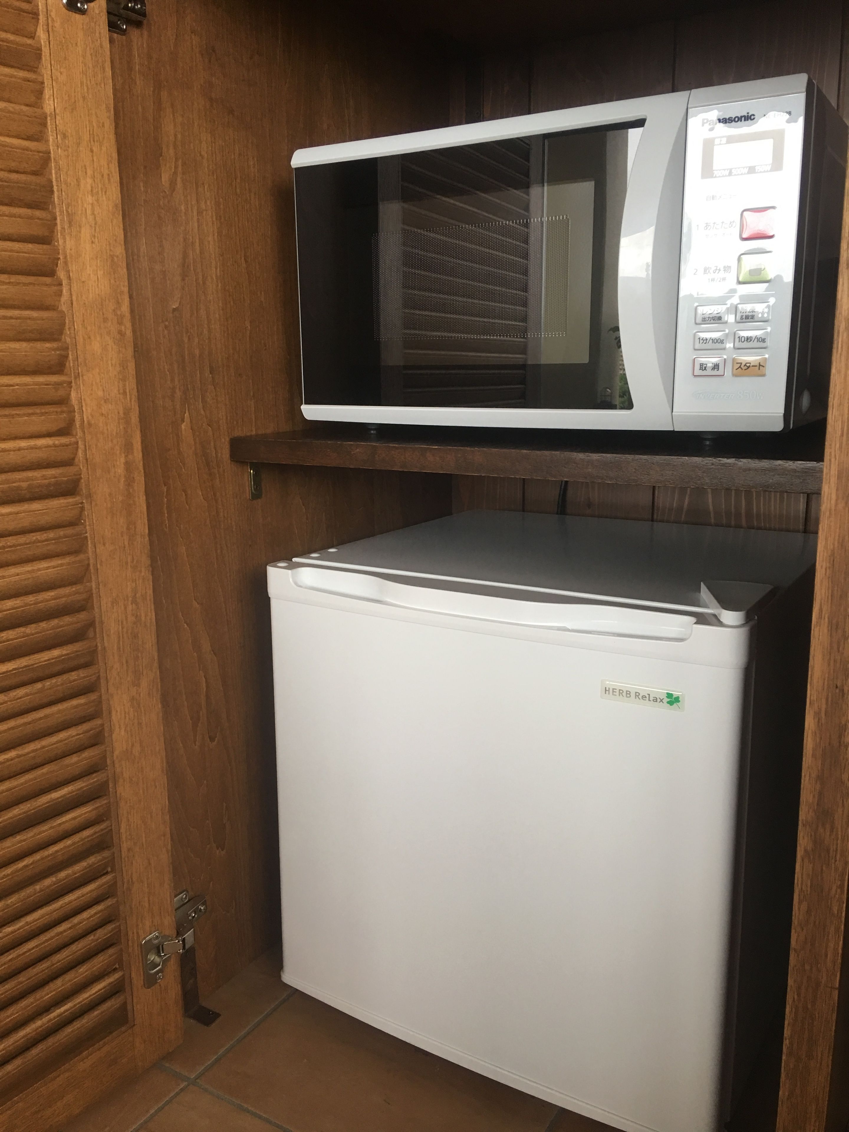 A compact refrigerator and microwave unit with a wooden panel and a metal handle.