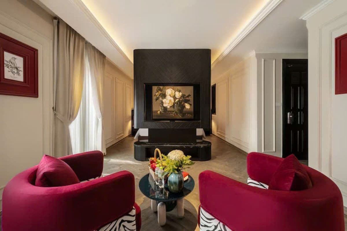 A modern living room with a fireplace, two red armchairs, and a coffee table with decorative items.
