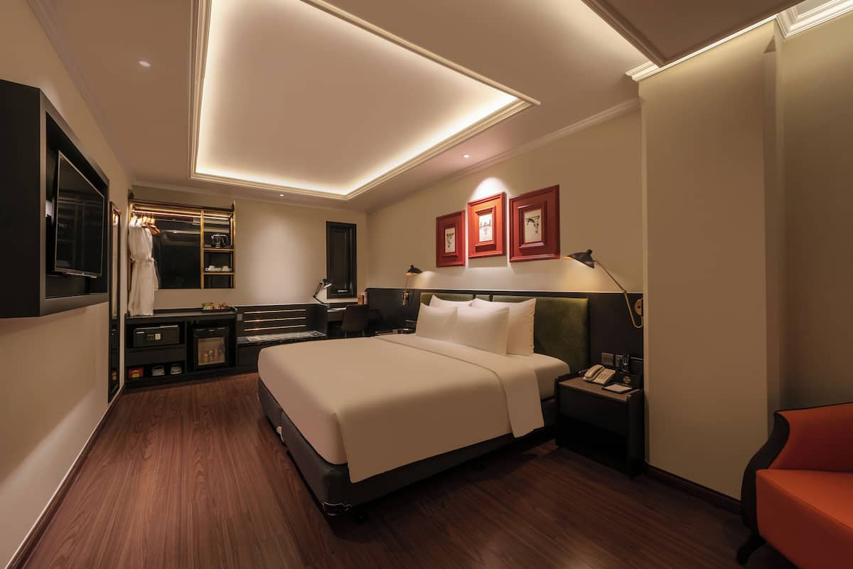 A modern hotel room with a large bed, bedside tables, a desk, and a chair.