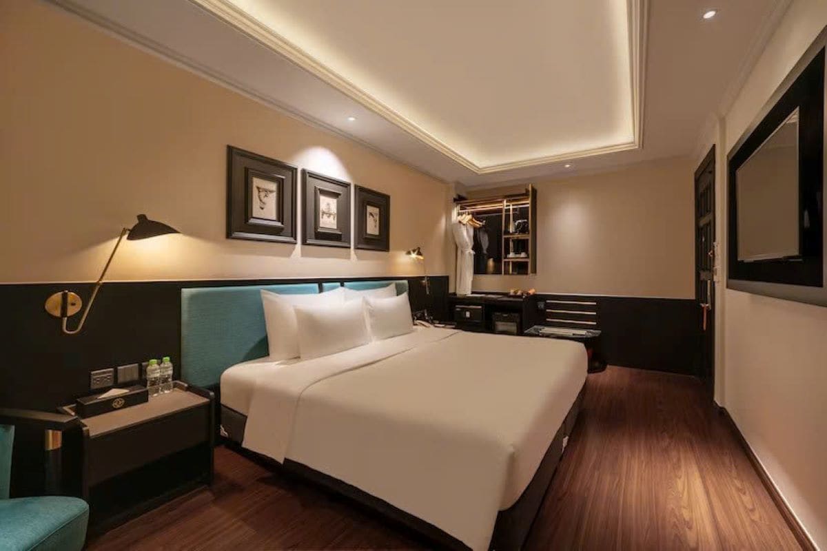 A hotel room with a large bed, bedside tables, a wardrobe, and a mirror.