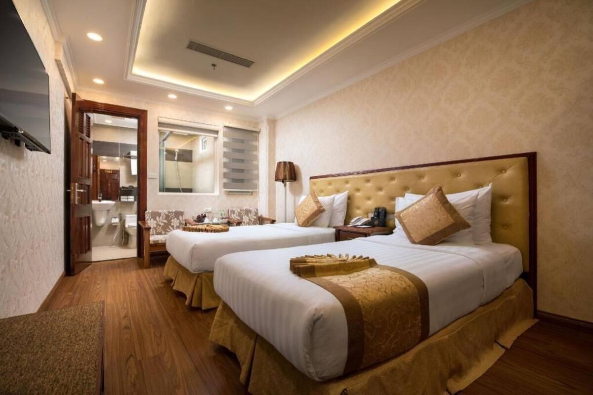 A hotel room with two beds, a bathroom, and a small sitting area.