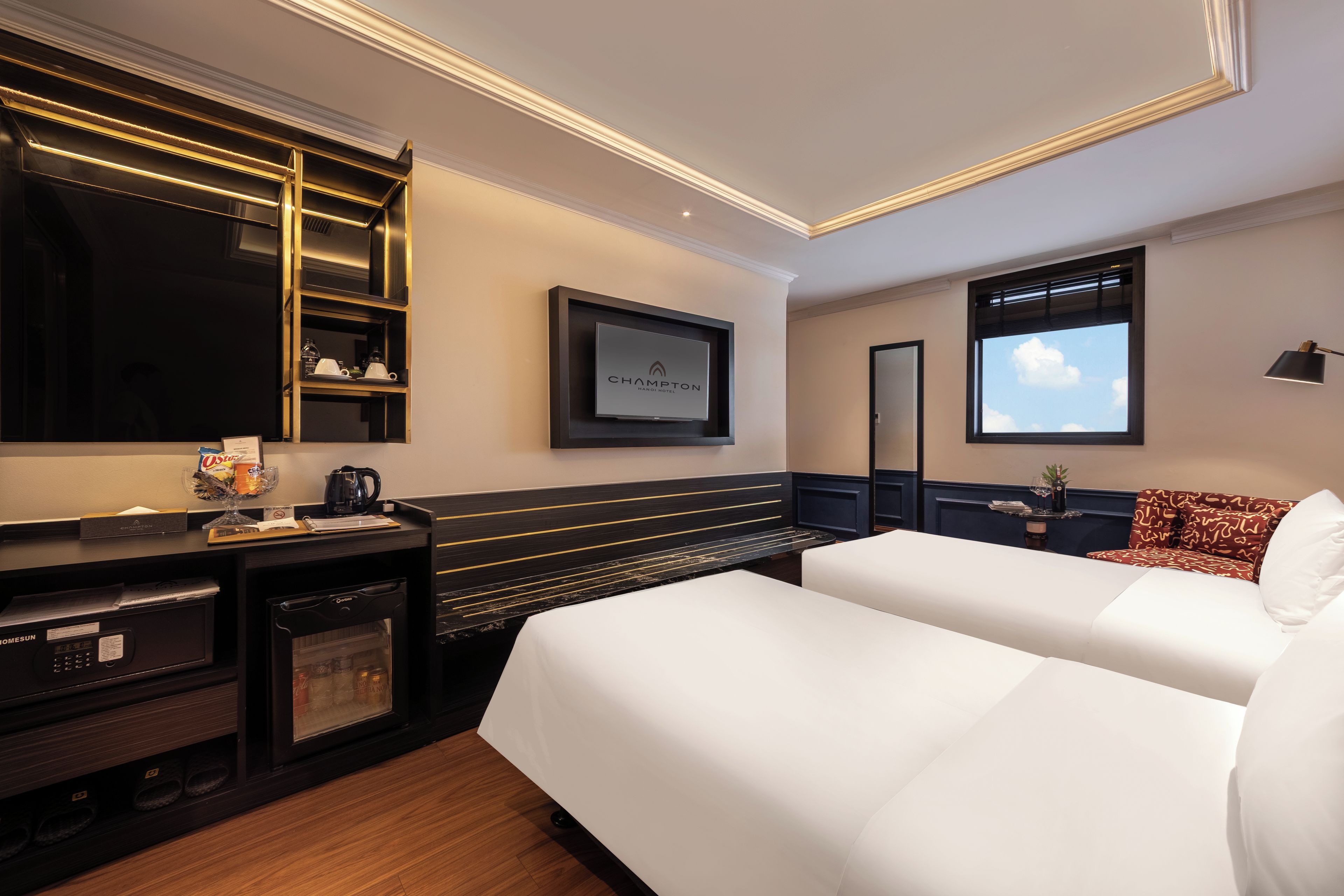 Una habitación de hotel con una cama, un escritorio con cafetera, un televisor y una ventana con vista al cielo.