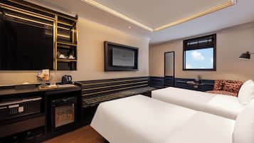 Una habitación de hotel con una cama, un escritorio con cafetera, un televisor y una ventana con vista al cielo.