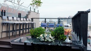 Una terraza en la azotea con mobiliario, un dispensador de bebidas y vistas a la ciudad.