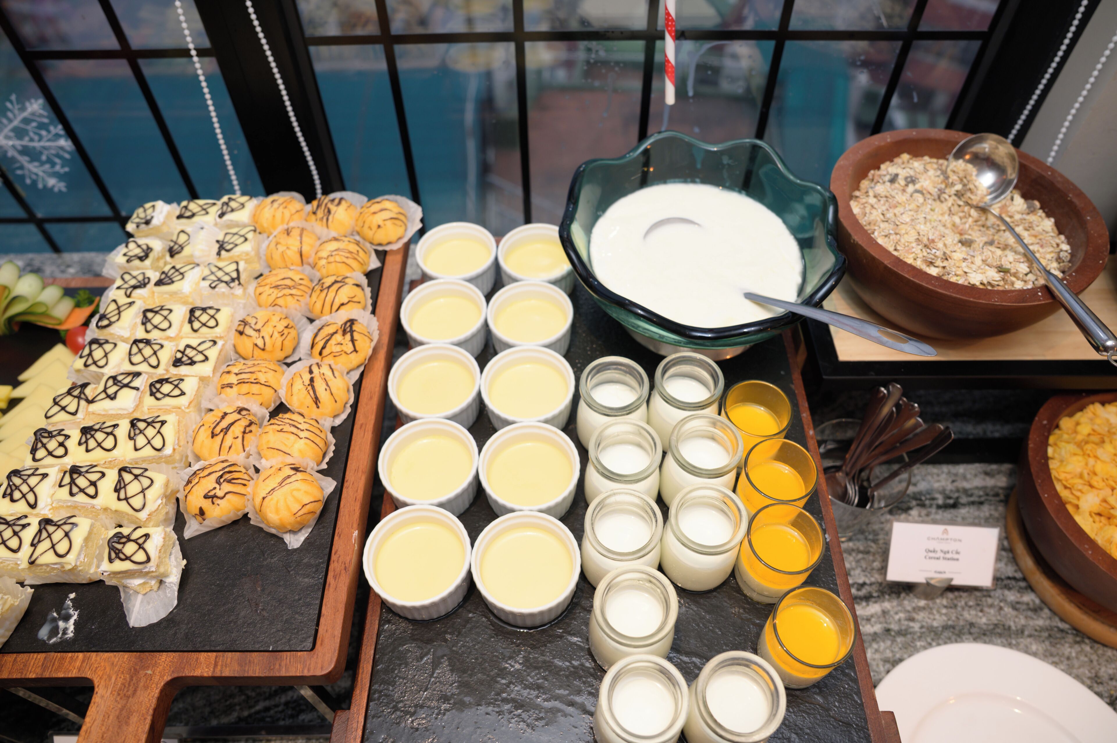 A buffet with various food items including pastries, custard, and cereal.