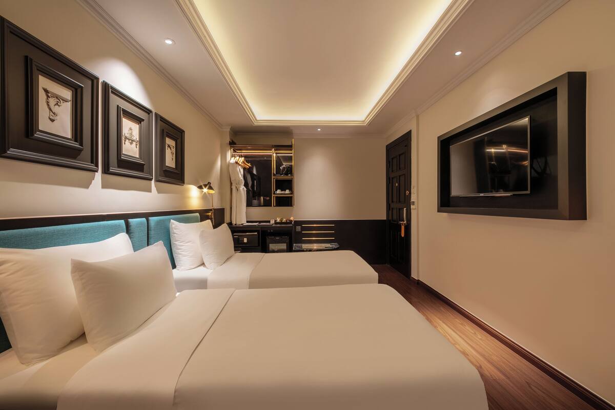 A hotel room with two beds, a walk-in closet, a TV, and framed artwork on the walls.