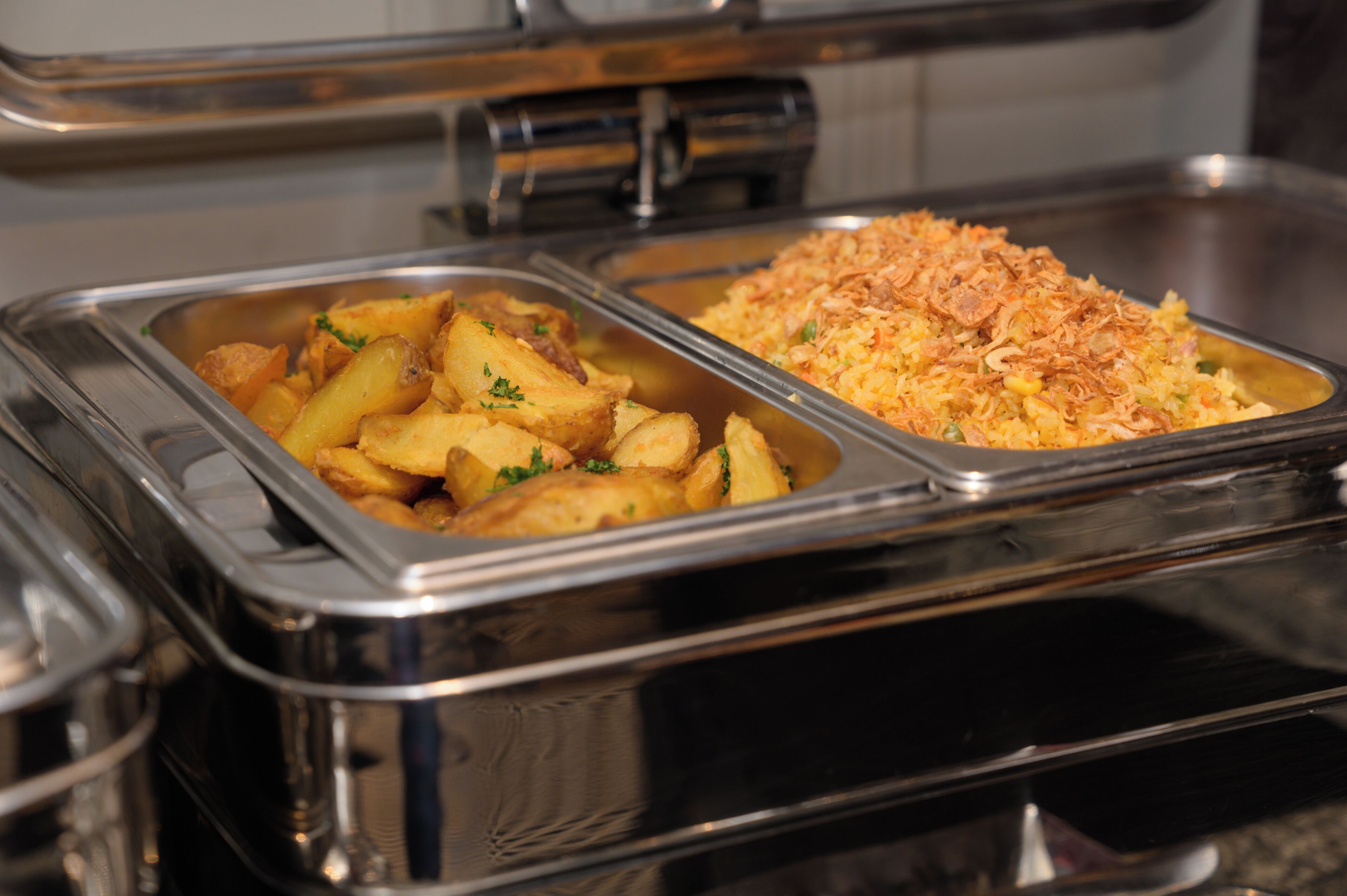 Un buffet avec deux plateaux en acier inoxydable contenant de la nourriture.