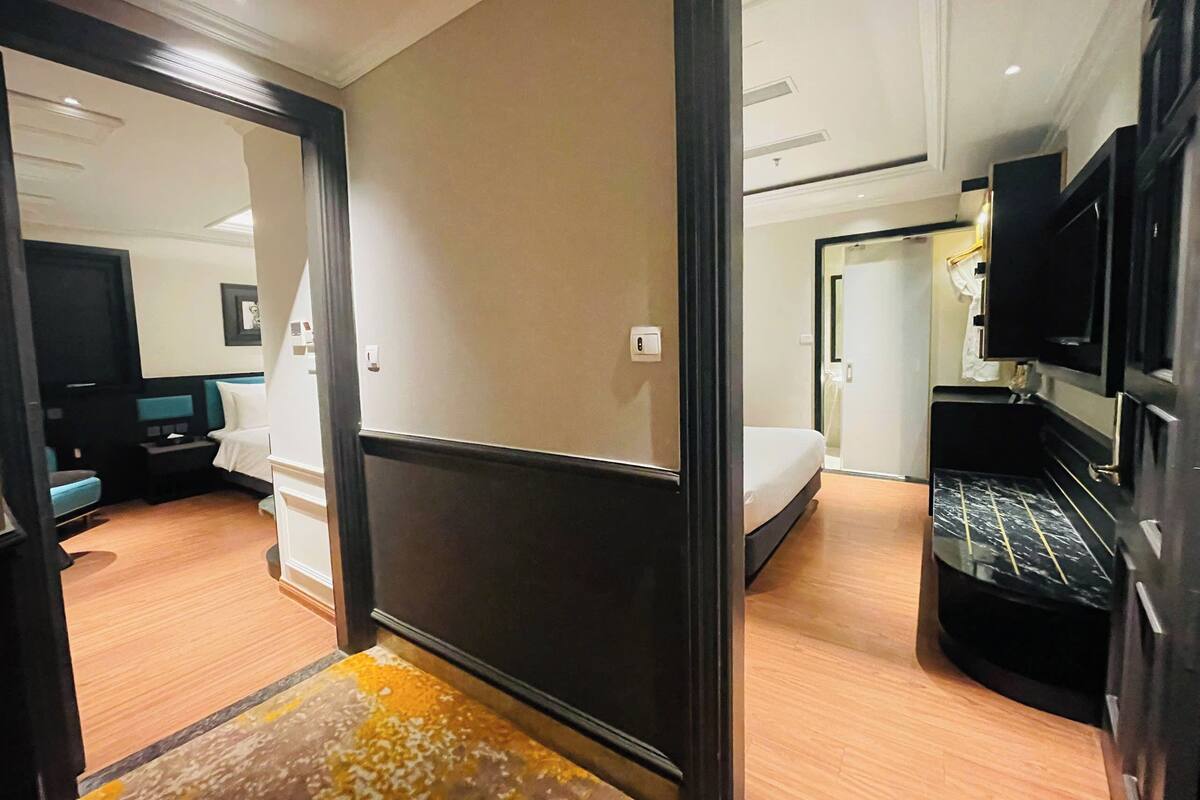 A hotel room with a bed, a TV, and a bathroom visible through an open door.