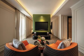 Una sala de estar moderna con un televisor de pantalla plana, dos sillones con cojines, una mesa de centro con un jarrón y una pared verde decorativa.