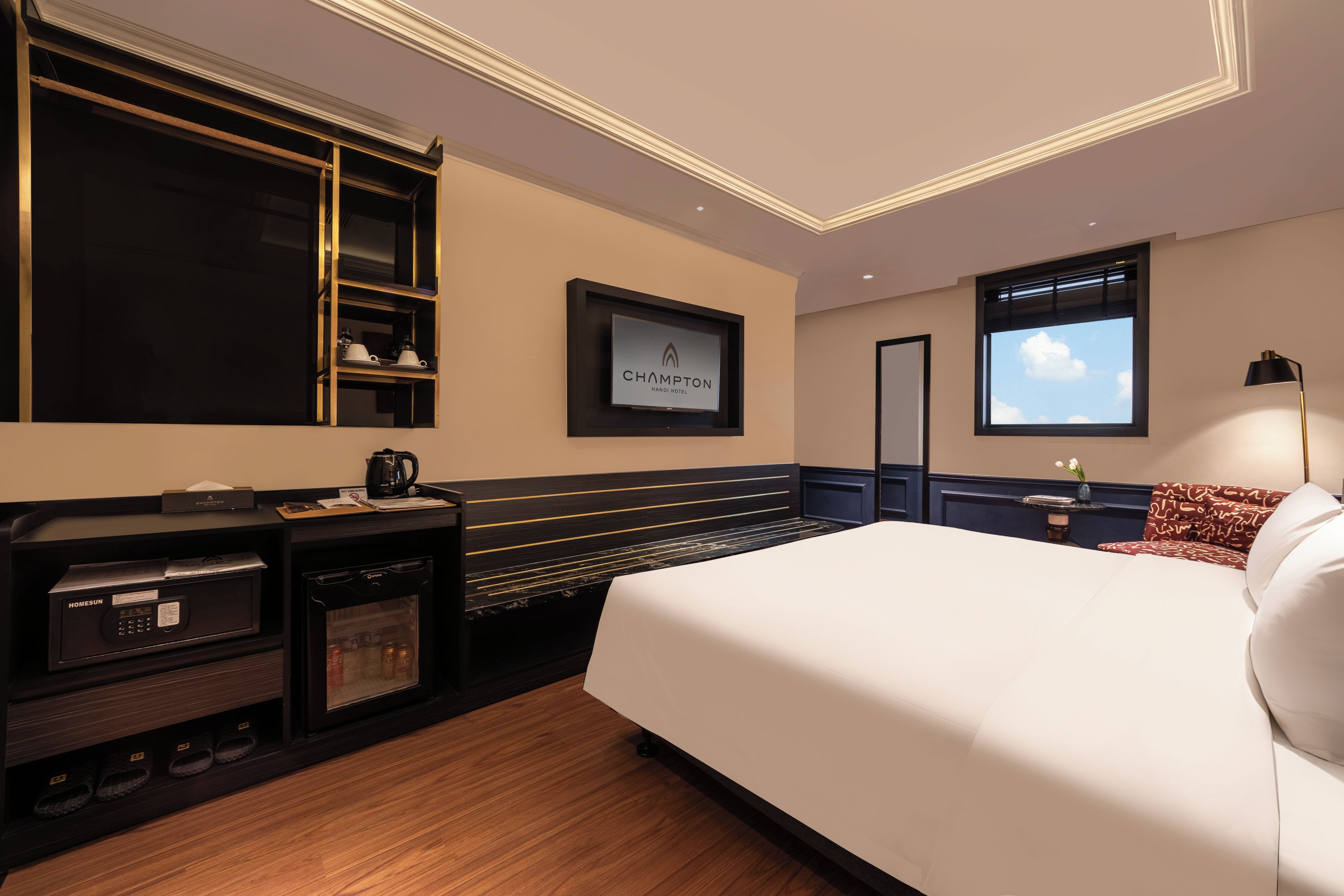 A hotel room with a bed, a minibar, a television, and a window with a view.