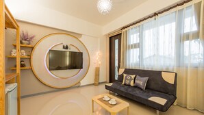 A modern living room with a round mirror, a sofa, a coffee table, and a TV. - Kingdom Love Bed and Breakfast (Ji'an)