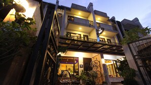 A multi-story building with balconies, outdoor seating, and potted plants. - Kingdom Love Bed and Breakfast (Ji'an)