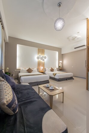 Una habitación de hotel moderna con dos camas, un sofá, una mesita de café y un aplique decorativo.
