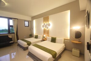 Una habitación de hotel con dos camas, un ventanal grande, una lámpara fijada a la pared y una mesita de noche pequeña.