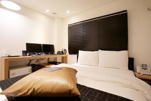 A hotel room with a bed, a desk with a computer, a telephone, and a window with blinds. - Kotel Sinchon (Seoul)