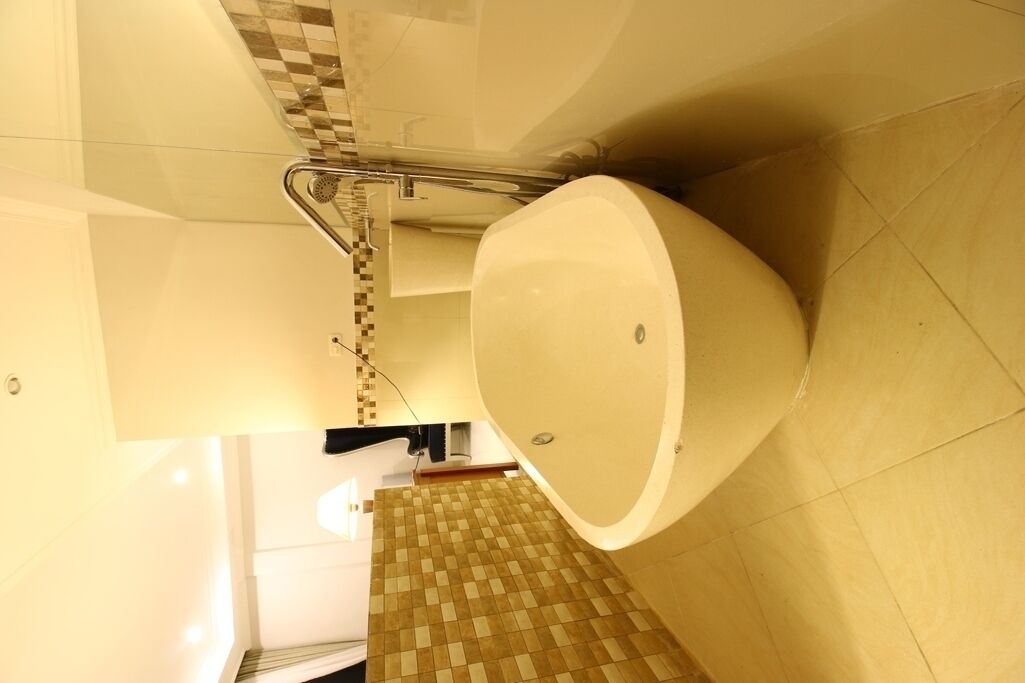 A bathroom with a large bathtub, a shower area, and a tiled floor.