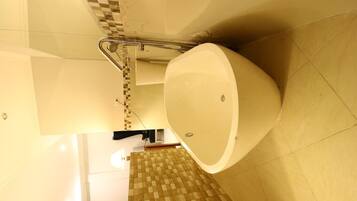 A bathroom with a large bathtub, a shower area, and a tiled floor.