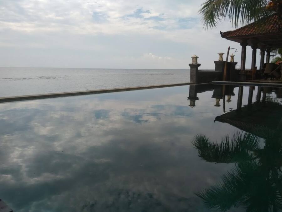 Vista despejada de una piscina con agua tranquila que refleja el cielo y las estructuras circundantes.