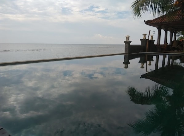 Vista despejada de una piscina con agua tranquila que refleja el cielo y las estructuras circundantes.